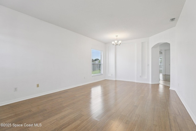 1609 Kestrel Ct, Rockledge, FL 32955 - spare room with arched walkways, a chandelier, light wood finished floors, and baseboards