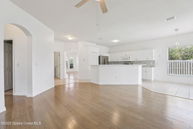 1609 Kestrel Ct, Rockledge, FL 32955 - unfurnished living room with light wood finished floors, arched walkways, ceiling fan, and baseboards