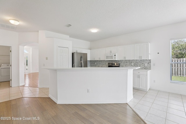 1609 Kestrel Ct, Rockledge, FL 32955 - kitchen with white microwave, freestanding refrigerator, washer / dryer, arched walkways, and light countertops