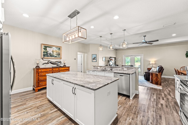 6435 Dixie Way, Mims, FL 32754 - kitchen featuring appliances with stainless steel finishes, a kitchen island with sink, light wood-style floors, white cabinets, and recessed lighting