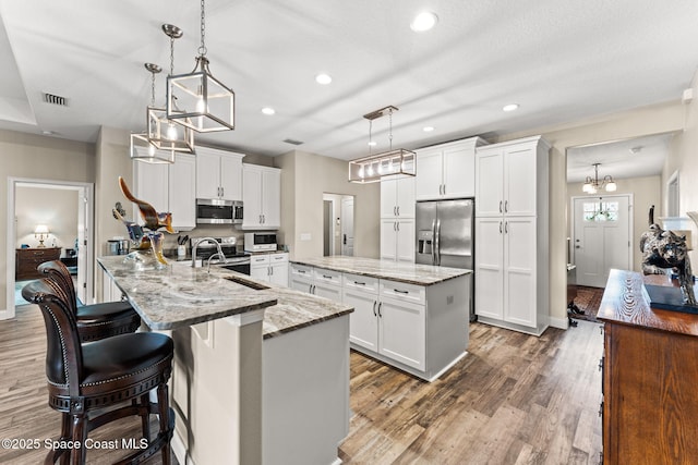 6435 Dixie Way, Mims, FL 32754 - kitchen with stainless steel appliances, a kitchen island, white cabinets, and recessed lighting