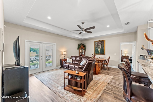 6435 Dixie Way, Mims, FL 32754 - living area featuring a raised ceiling, a ceiling fan, french doors, light wood-style flooring, and baseboards