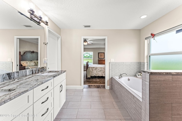 6435 Dixie Way, Mims, FL 32754 - ensuite bathroom with double vanity, a garden tub, healthy amount of natural light, and a ceiling fan