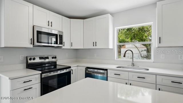 4415 Shaw Ave, Titusville, FL 32780 - kitchen featuring stainless steel appliances, a sink, light countertops, and white cabinets
