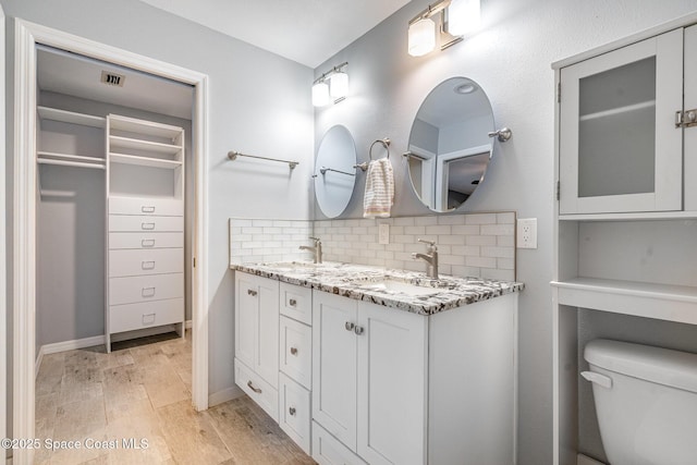 490 Candlestick Ave NE, Palm Bay, FL 32907 - bathroom with decorative backsplash, double vanity, wood finished floors, toilet, and a walk in closet