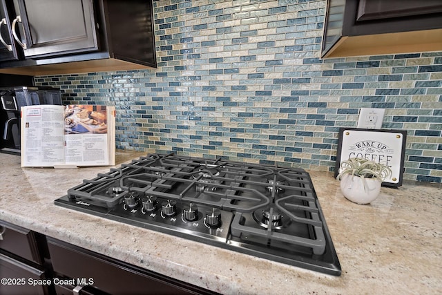 7914 Creshire Ct, Melbourne, FL 32940 - kitchen view of black gas cooktop, backsplash, dark brown cabinetry, and light stone countertops