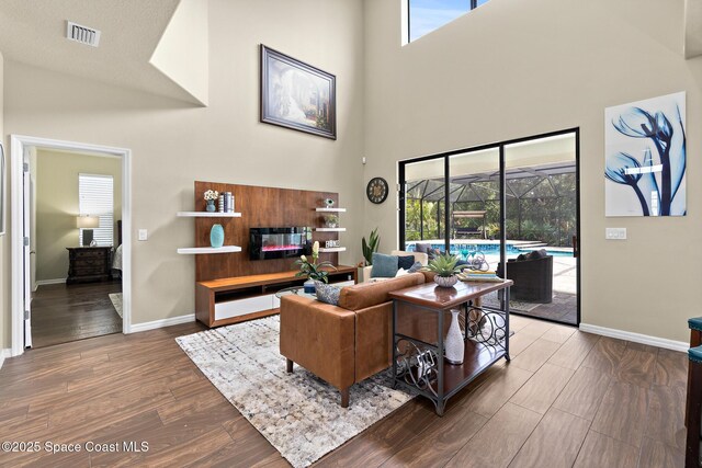 7914 Creshire Ct, Melbourne, FL 32940 - living room featuring a towering ceiling, baseboards, dark wood-style flooring, and a sunroom