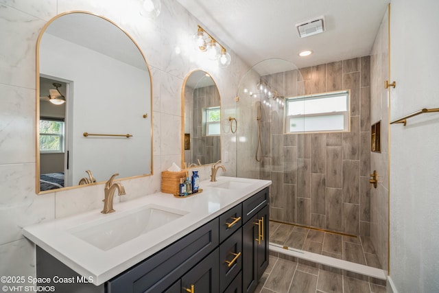201 NE 3rd St, Satellite Beach, FL 32937 - full bath with double vanity, a walk in shower, wood finish floors, connected bathroom, and tile walls