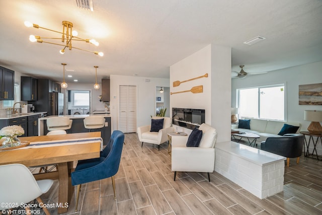 201 NE 3rd St, Satellite Beach, FL 32937 - dining area featuring a chandelier, light wood-style floors, a ceiling fan, and a glass covered fireplace