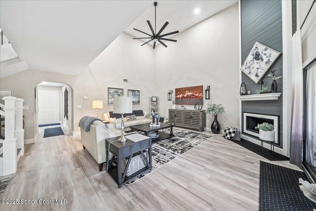 977 Osprey Dr, Melbourne, FL 32940 - living area featuring arched walkways, vaulted ceiling, a ceiling fan, wood finished floors, and a fireplace