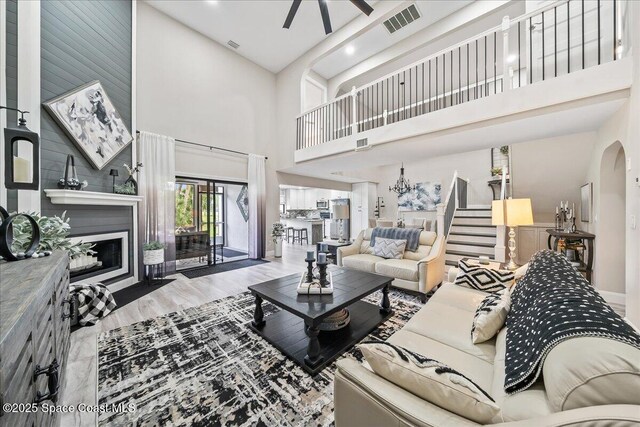 977 Osprey Dr, Melbourne, FL 32940 - living room with a high ceiling, a glass covered fireplace, ceiling fan, wood finished floors, and arched walkways