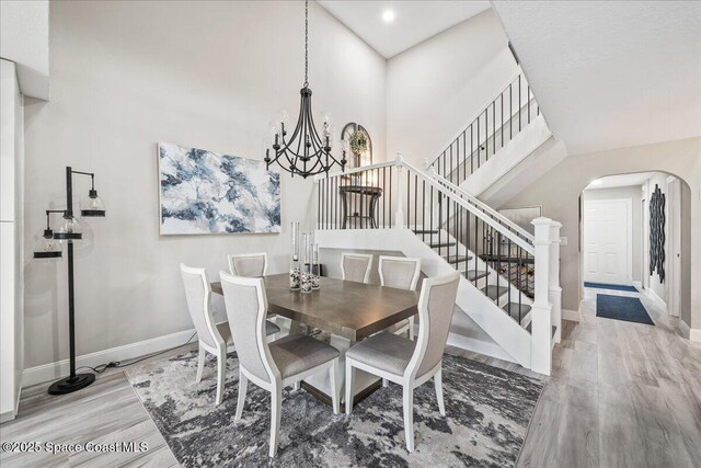 977 Osprey Dr, Melbourne, FL 32940 - dining room featuring a chandelier, arched walkways, stairway, wood finished floors, and baseboards