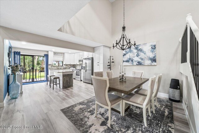 977 Osprey Dr, Melbourne, FL 32940 - dining space featuring a chandelier, baseboards, and light wood-style flooring