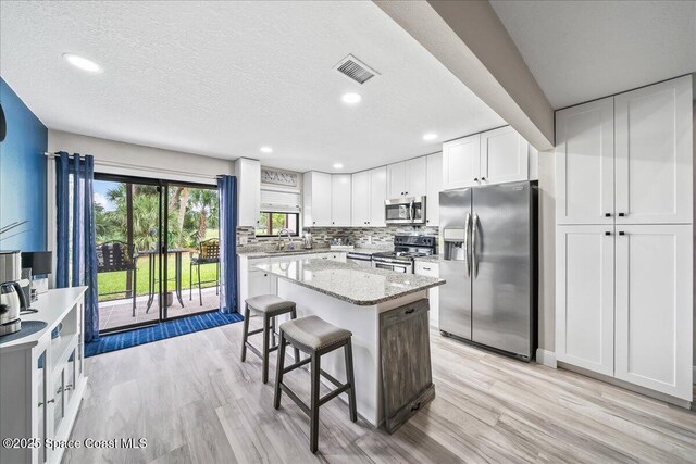 977 Osprey Dr, Melbourne, FL 32940 - kitchen featuring stainless steel appliances, a sink, light wood-style floors, a breakfast bar, and recessed lighting