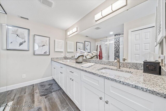 977 Osprey Dr, Melbourne, FL 32940 - full bathroom featuring double vanity, wood finished floors, baseboards, and a shower stall