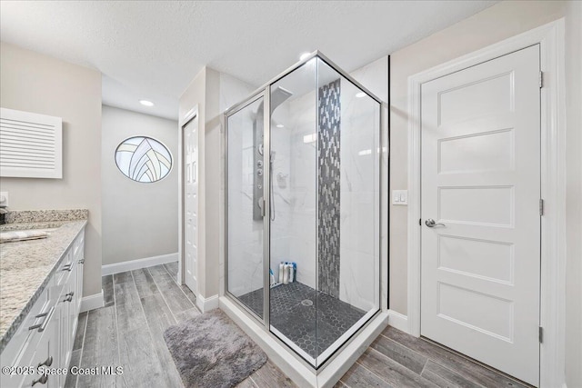 977 Osprey Dr, Melbourne, FL 32940 - bathroom featuring wood finished floors, vanity, a shower stall, baseboards, and a textured ceiling