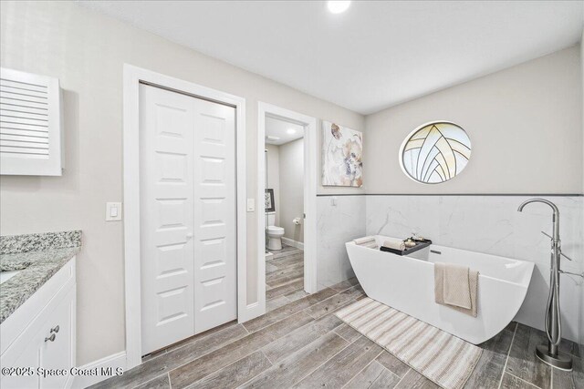 977 Osprey Dr, Melbourne, FL 32940 - full bath with wood finished floors, a freestanding tub, toilet, vanity, and tile walls