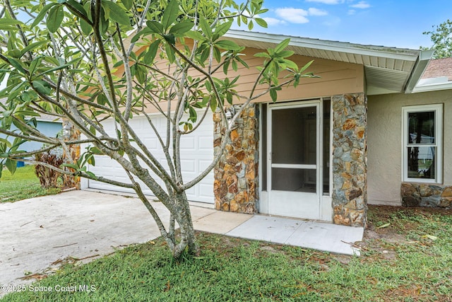 790 Alfonso Ave SE, Palm Bay, FL 32909 - view of exterior entry featuring stone siding, stucco siding, an attached garage, and driveway