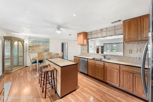 790 Alfonso Ave SE, Palm Bay, FL 32909 - kitchen featuring stainless steel dishwasher, a sink, light wood-style floors, a kitchen island, and a breakfast bar