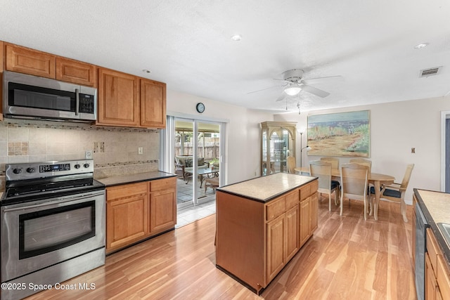 790 Alfonso Ave SE, Palm Bay, FL 32909 - kitchen with appliances with stainless steel finishes, light wood-type flooring, ceiling fan, decorative backsplash, and a center island