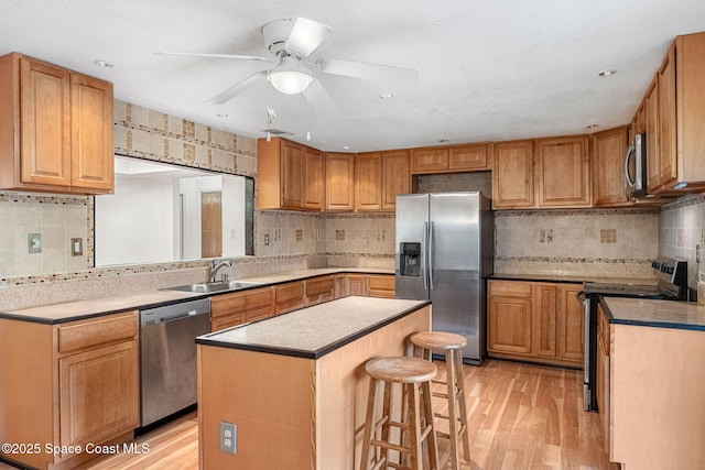 790 Alfonso Ave SE, Palm Bay, FL 32909 - kitchen featuring appliances with stainless steel finishes, decorative backsplash, a sink, a breakfast bar, and light wood-type flooring