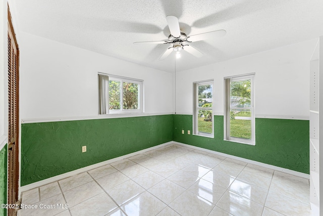 790 Alfonso Ave SE, Palm Bay, FL 32909 - tiled empty room with a ceiling fan, baseboards, a textured ceiling, and wainscoting