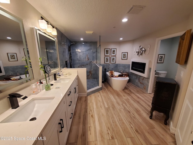 93 Delannoy Ave Unit 601, Cocoa, FL 32922 - bathroom with a fireplace, a stall shower, wood finished floors, double vanity, and a soaking tub