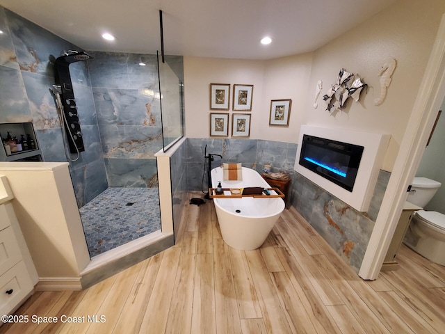 93 Delannoy Ave Unit 601, Cocoa, FL 32922 - full bathroom featuring tile walls, wood finished floors, a glass covered fireplace, a walk in shower, and recessed lighting