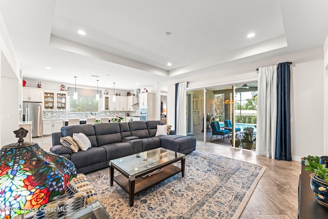 14880 Ellingsworth Ln, Winter Garden, FL 34787 - living area featuring a tray ceiling, recessed lighting, baseboards, and light tile patterned flooring