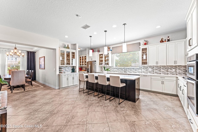 14880 Ellingsworth Ln, Winter Garden, FL 34787 - kitchen with stainless steel fridge, a chandelier, decorative backsplash, light countertops, and a center island