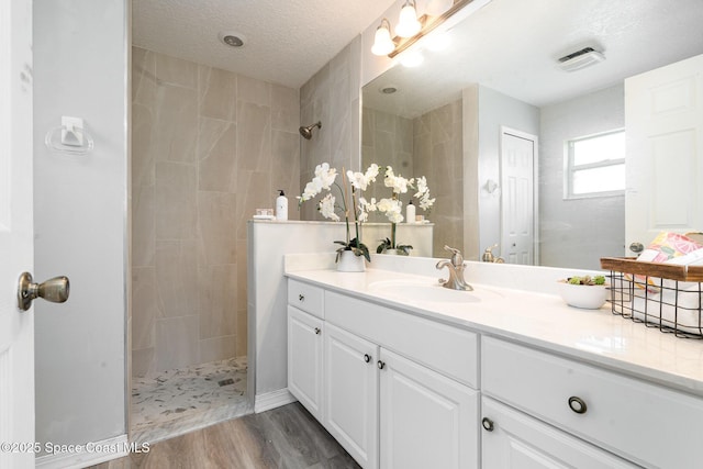 1102 Bainbury Ln, Melbourne, FL 32904 - bathroom with vanity, a walk in shower, wood finished floors, and a textured ceiling
