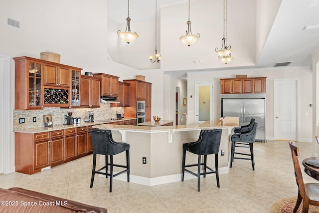 4022 Tradewinds Trl, Merritt Island, FL 32953 - kitchen with built in appliances, tasteful backsplash, a breakfast bar area, brown cabinetry, and a high ceiling