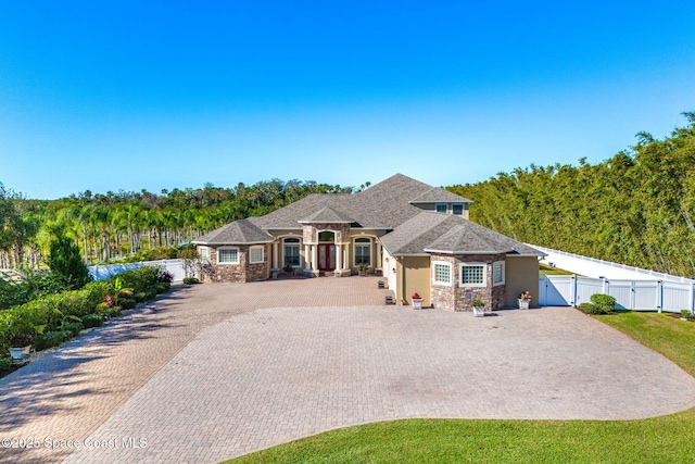 4022 Tradewinds Trl, Merritt Island, FL 32953 - view of front of home featuring stone siding, a gate, decorative driveway, and stucco siding