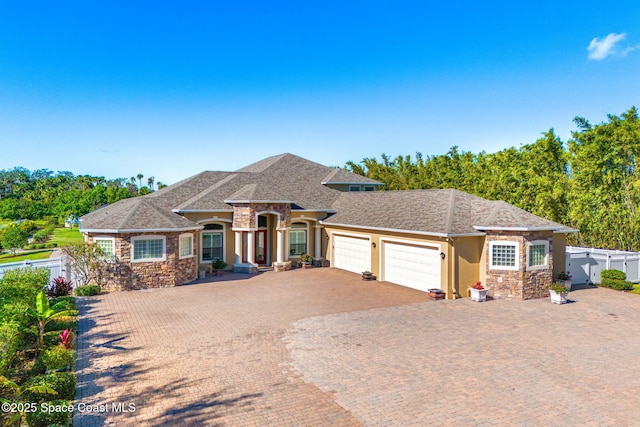 4022 Tradewinds Trl, Merritt Island, FL 32953 - view of front of house with stone siding, an attached garage, decorative driveway, and stucco siding