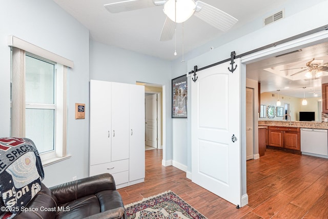 8700 Ridgewood Ave Unit Ph2B, Cape Canaveral, FL 32920 - living area with a ceiling fan, wood finished floors, a barn door, and plenty of natural light