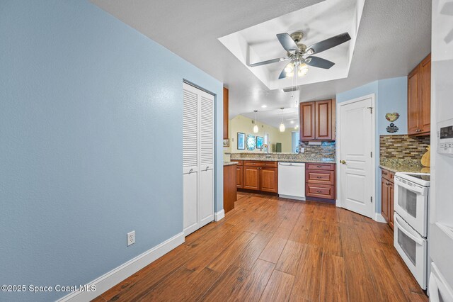 8700 Ridgewood Ave Unit Ph2B, Cape Canaveral, FL 32920 - kitchen with white appliances, backsplash, brown cabinets, dark wood-style flooring, and a ceiling fan