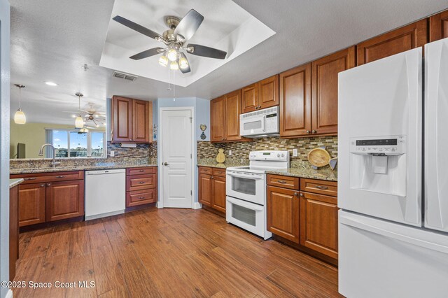 8700 Ridgewood Ave Unit Ph2B, Cape Canaveral, FL 32920 - kitchen with white appliances, a tray ceiling, a ceiling fan, and brown cabinetry