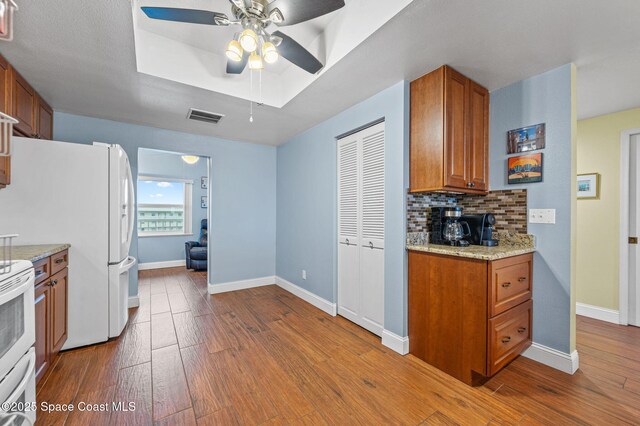 8700 Ridgewood Ave Unit Ph2B, Cape Canaveral, FL 32920 - kitchen featuring brown cabinets, wood finished floors, ceiling fan, and light stone countertops