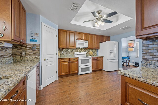 8700 Ridgewood Ave Unit Ph2B, Cape Canaveral, FL 32920 - kitchen with white appliances, a raised ceiling, brown cabinetry, decorative backsplash, and wood finished floors