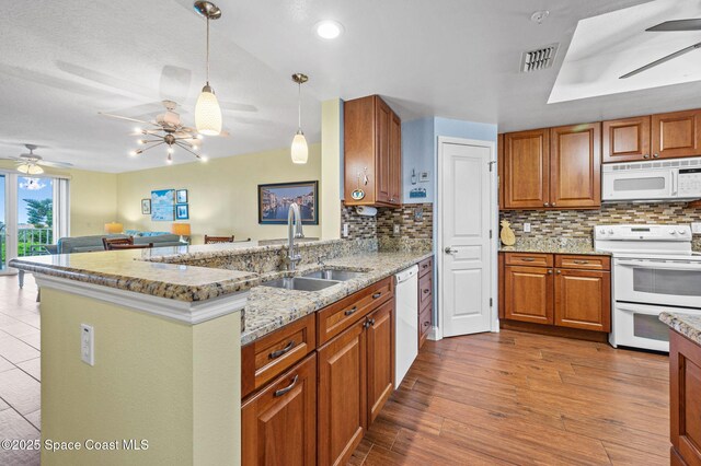 8700 Ridgewood Ave Unit Ph2B, Cape Canaveral, FL 32920 - kitchen featuring white appliances, ceiling fan, brown cabinets, and backsplash