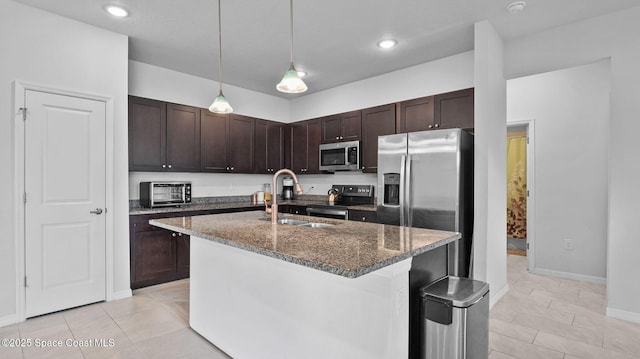 837 Wakaw Ln SW, Palm Bay, FL 32908 - kitchen with appliances with stainless steel finishes, dark stone counters, dark brown cabinets, decorative light fixtures, and a kitchen island with sink