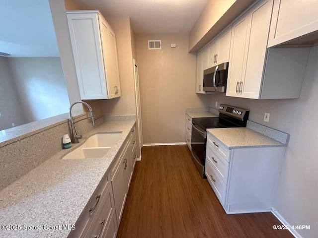 5663 Star Rush Dr Unit 107, Melbourne, FL 32940 - kitchen featuring stainless steel appliances, a sink, dark wood finished floors, baseboards, and white cabinetry