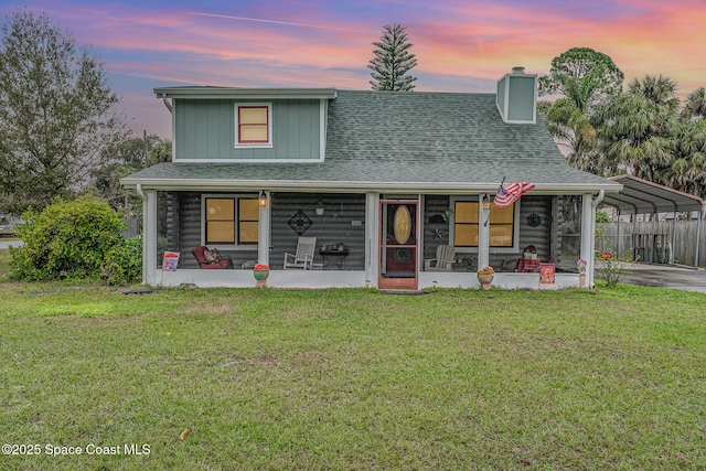 4390 Everglades St, Cocoa, FL 32927 - view of front of property featuring a detached carport, a chimney, a yard, a shingled roof, and a sunroom