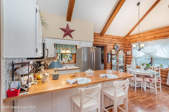 4390 Everglades St, Cocoa, FL 32927 - kitchen with rustic walls, freestanding refrigerator, a peninsula, wood finished floors, and hanging light fixtures