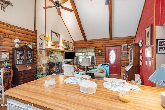 4390 Everglades St, Cocoa, FL 32927 - dining area featuring log walls, ceiling fan, a stone fireplace, beamed ceiling, and high vaulted ceiling