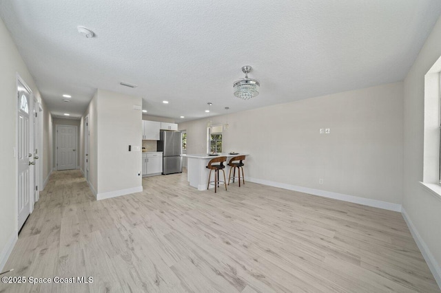 414 Marquis St, Melbourne, FL 32901 - unfurnished living room with light wood-style floors, recessed lighting, baseboards, and a textured ceiling