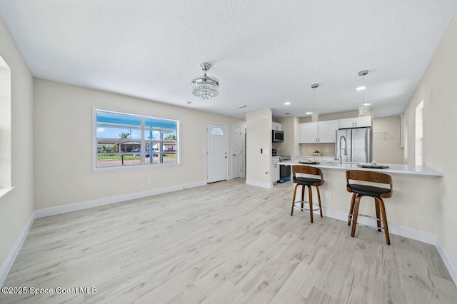 414 Marquis St, Melbourne, FL 32901 - kitchen featuring appliances with stainless steel finishes, light countertops, a breakfast bar area, light wood finished floors, and a textured ceiling