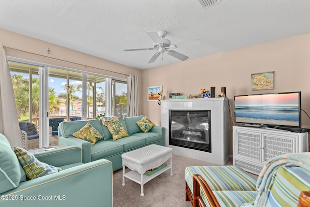 243 Forecast Ln Unit 4-21, Rockledge, FL 32955 - living room featuring carpet, a tiled fireplace, a ceiling fan, and a textured ceiling