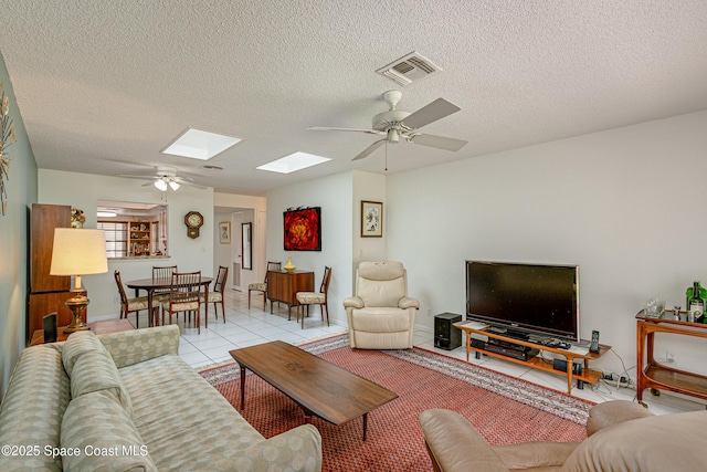 290 Paradise Blvd Unit 61, Indialantic, FL 32903 - living area featuring ceiling fan, light tile patterned flooring, a skylight, baseboards, and a textured ceiling