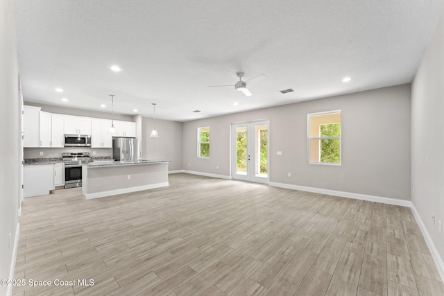 1427 Damon Rd SE, Palm Bay, FL 32909 - unfurnished living room featuring healthy amount of natural light, ceiling fan, baseboards, light wood-type flooring, and recessed lighting